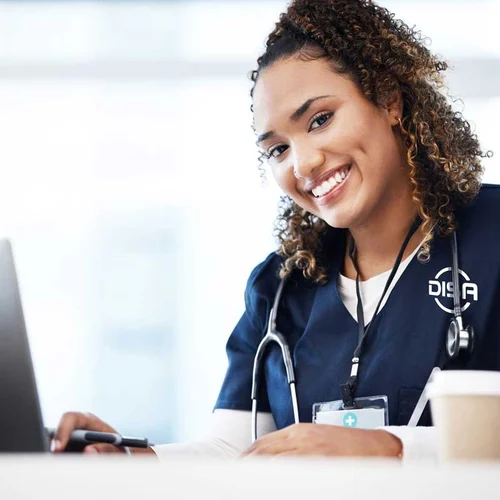 Nurse sitting at a desk and smiling, wearing DISA scrubs