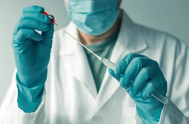 medical technician putting a swab with oral fluid into a test tube