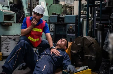Worker had accident unconscious on the floor at factory. Male engineer supervisor talking on walkie talkie for help. Safety in Factory industrial and drug testing concept.