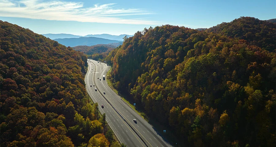 trucks and cars driving on highway with skyline