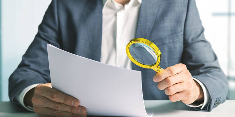 background check businessman reviewing resume with magnifying glass