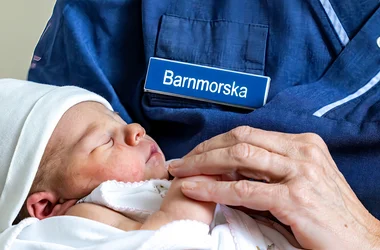 Barnmorska som håller i en bebis