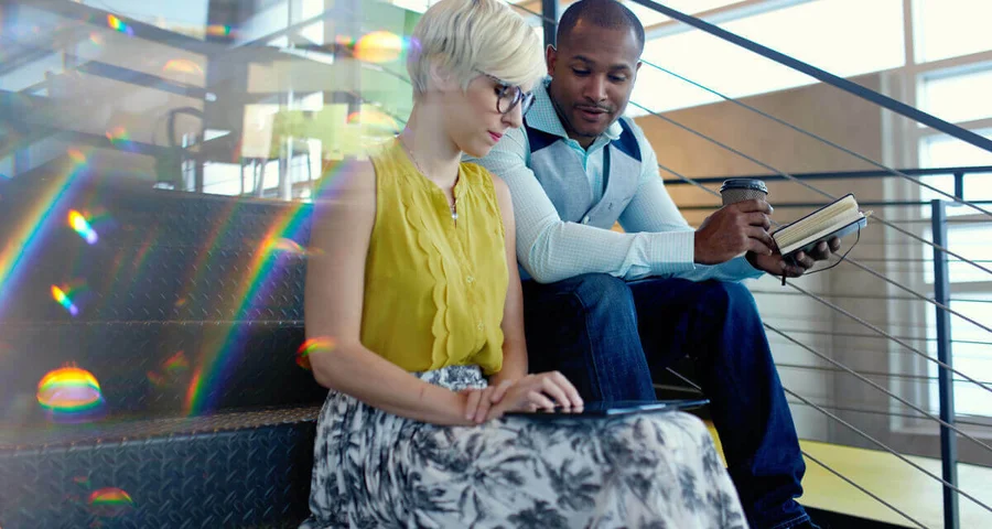 Coworkers sitting on stairs looking at a tablet together