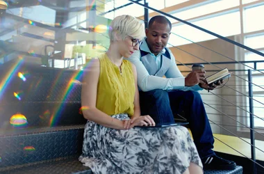 Coworkers sitting on stairs looking at a tablet together