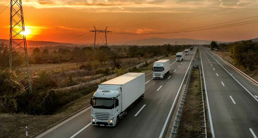 18-wheeler trucks driving in a line on the highway at sunset