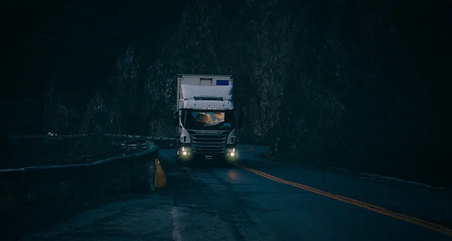 Truck driving on a dark and winding road at night