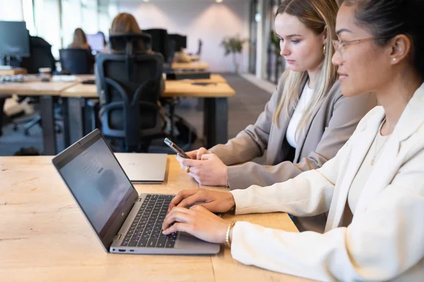 Two female employees working on a laptop