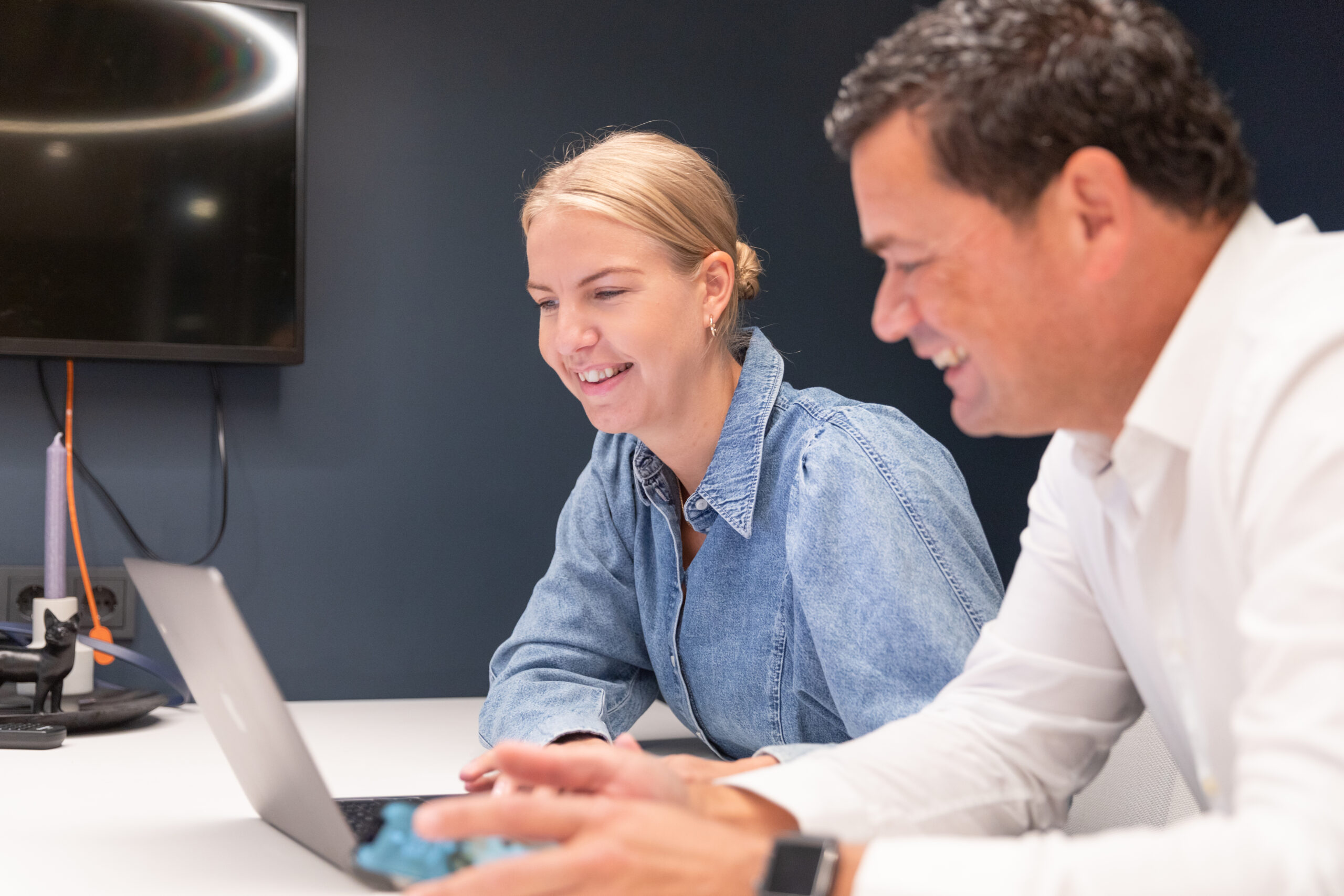 two coworkers smiling looking at laptop