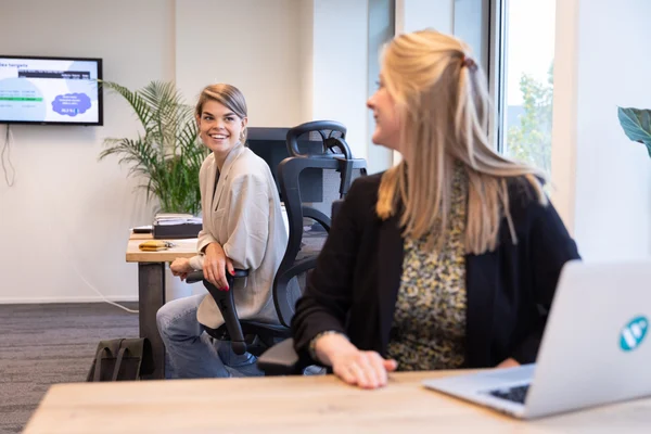 Two employees are sitting at their workstations and talking about how the tests can be carried out in the best way