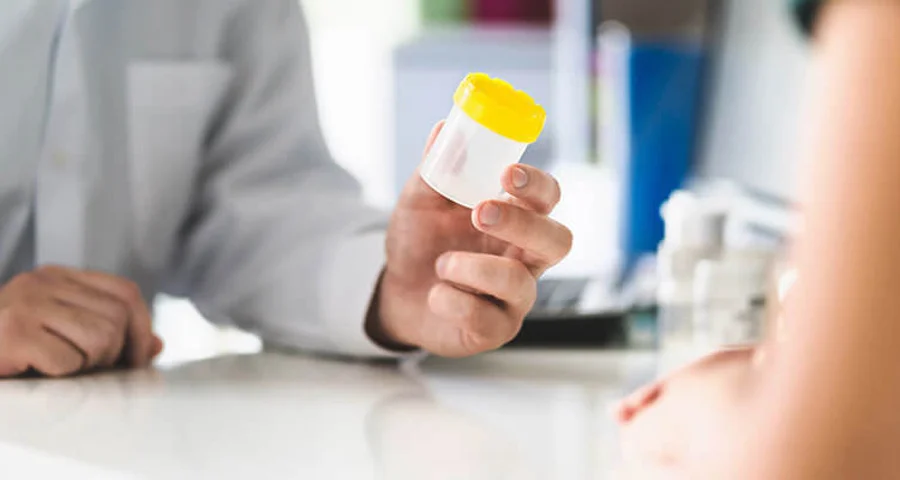 man giving a drug test specimen container to a patient