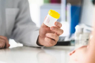 man giving a drug test specimen container to a patient