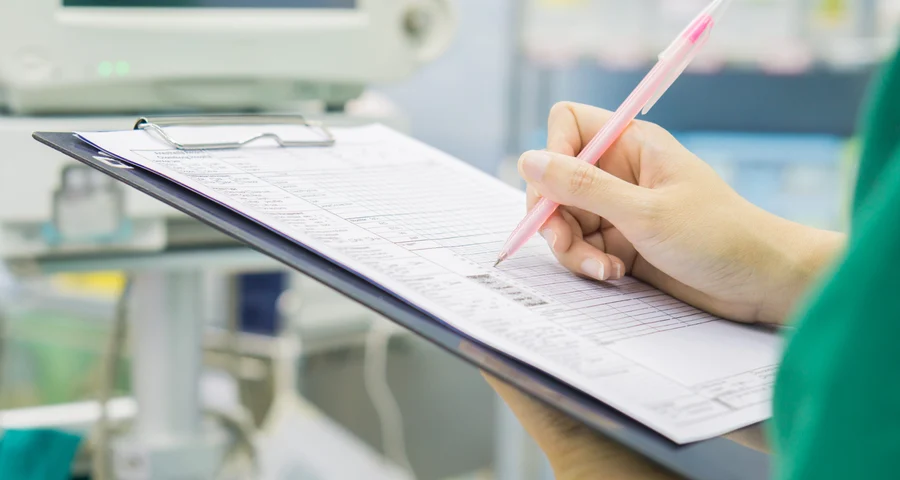 Een zorgmedewerker die iets aankruist op een klembord
