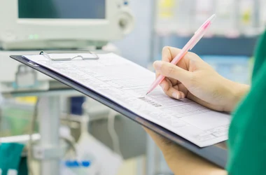 A care worker ticking something off on a clipboard.