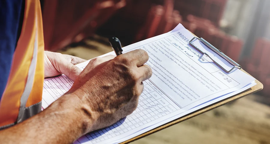 worker wearing a safety vest making notes on a clipboard